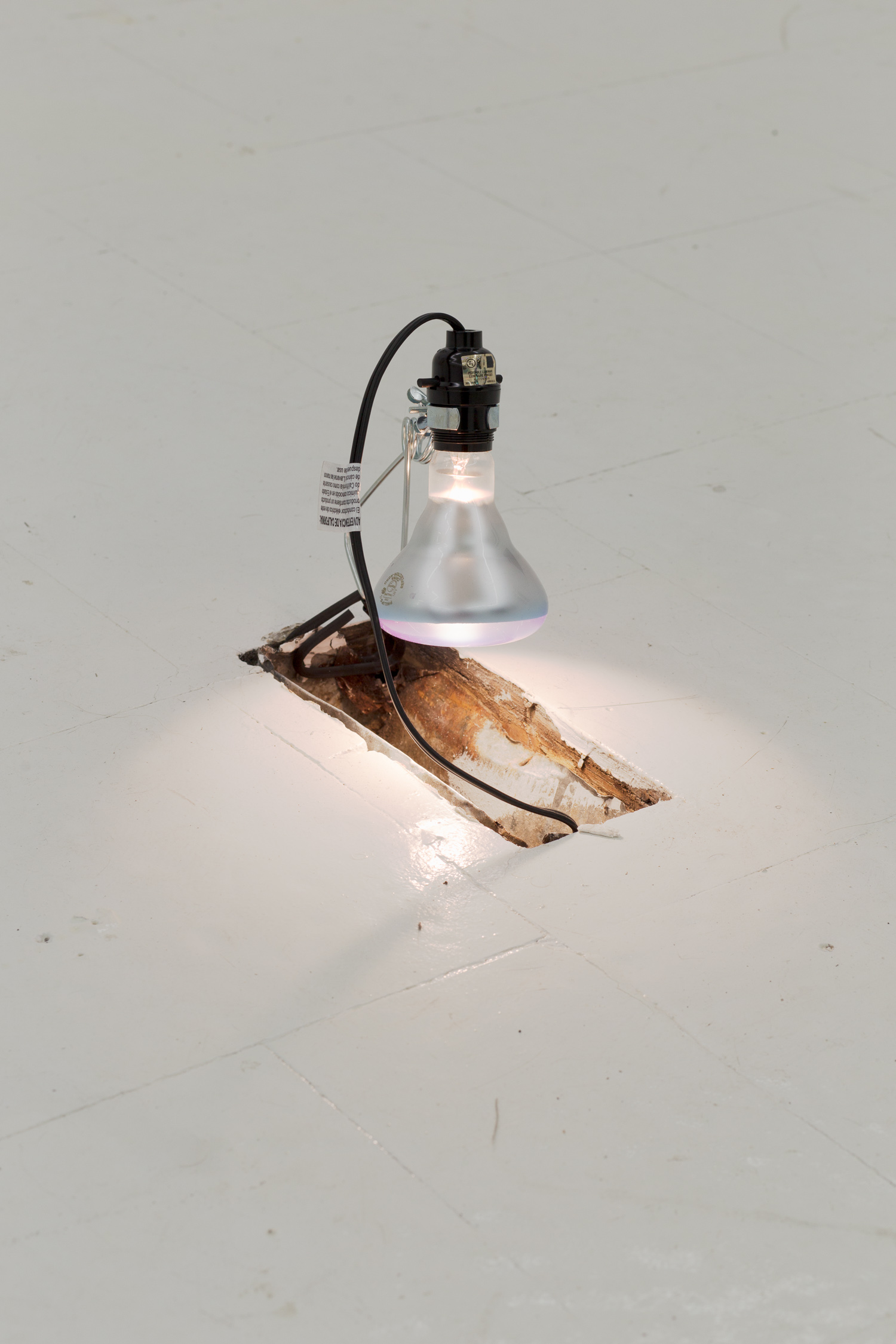 An A/C vent in the floor is illuminated by a clamp light